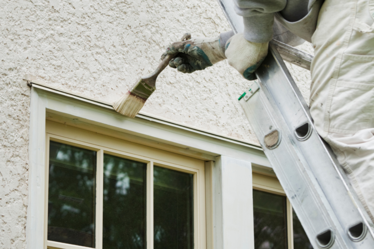 A trade person painting an exterior window