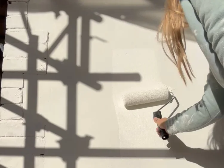 Applying masonry paint to an exterior wall