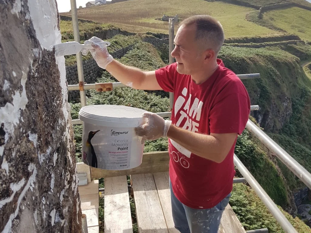 Applying masonry paint to exterior walls