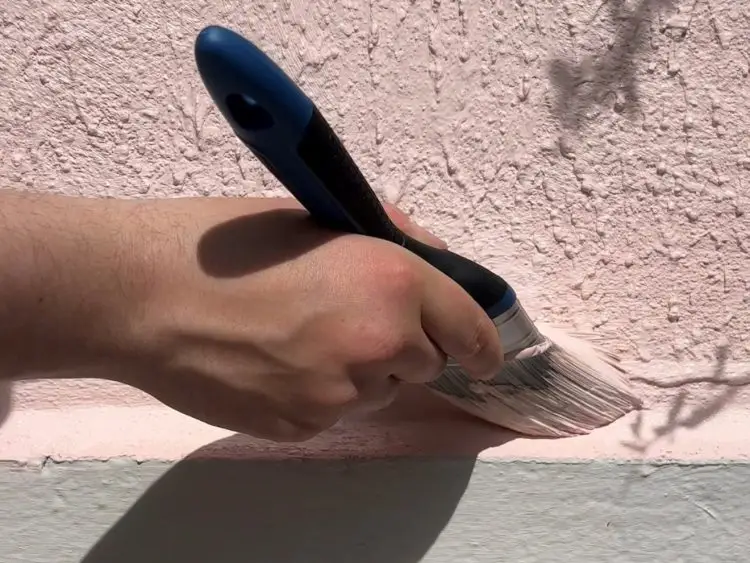 Paint brush that is painting an exterior wall