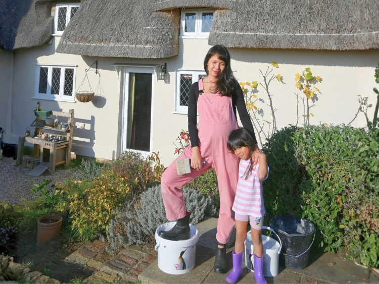 Susie in front of her house after painting the exterior walls