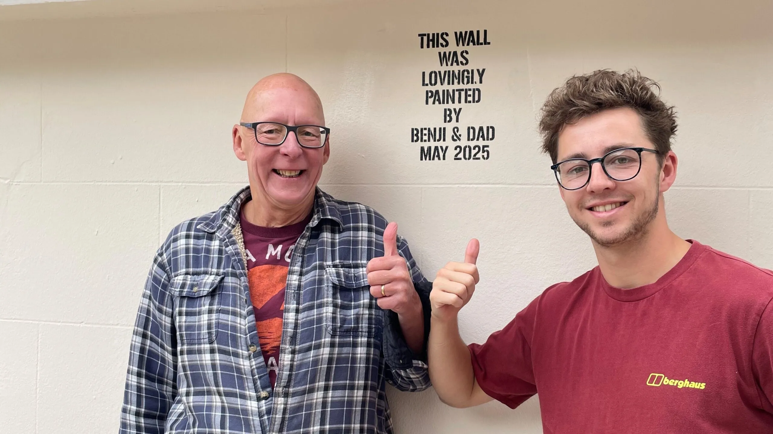 Two men standing outside a wall they have painted