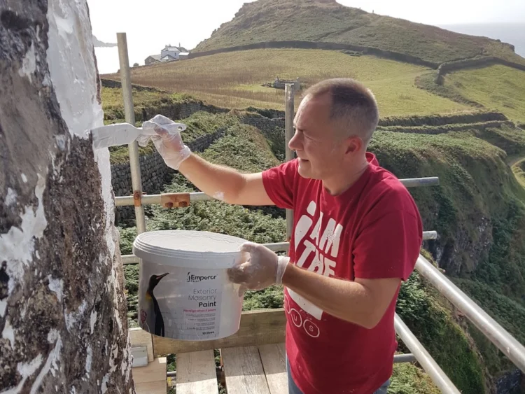 Using a brush to paint an exterior wall